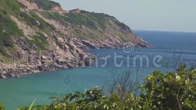 海岛上的岩石悬崖和碧水景观。 绿色的海岛，岩石海岸和碧水在清晰的天际线上。